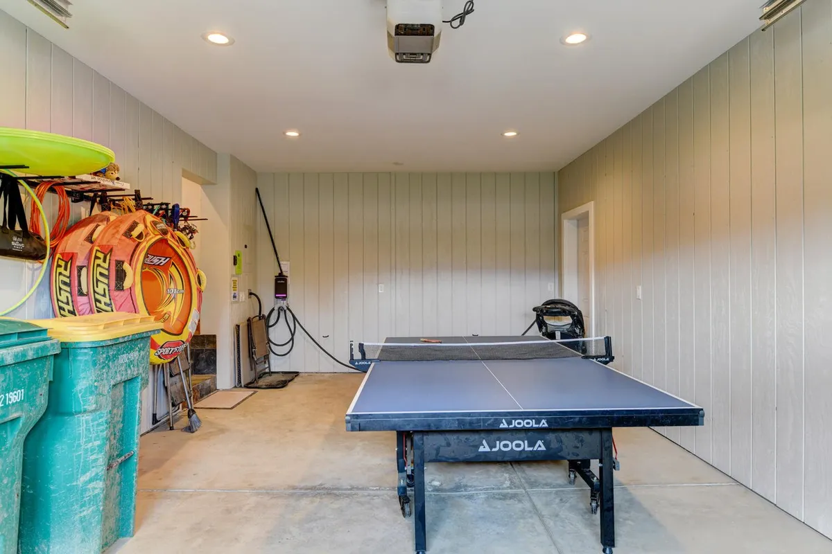 This image presents a view of the garage interior, including a ping pong table, colorful outdoor gear, and garage tools. The space reflects a functional area for gear storage and family-friendly activities, with ample space for prepping or winding down after an adventure.