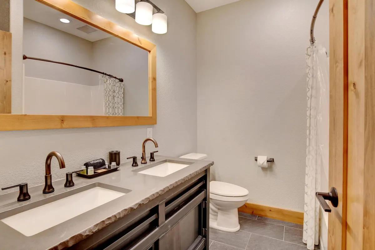 A serene, spa-quality bathroom featuring double vanity sinks, a large mirror, and modern fixtures set against warm wooden accents. The space feels calm and inviting, reflecting a commitment to relaxation and luxury. The arrangement suggests both functionality and a touch of indulgence, ideal for family routines or quiet personal moments.